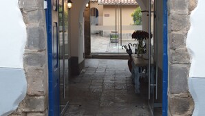 An entrance with a stone archway, a blue door, and a small table with a vase of flowers.