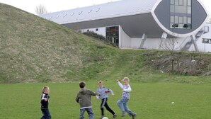 Un bâtiment moderne doté d’un toit incurvé original et d’un terrain herbeux devant l’entrée.