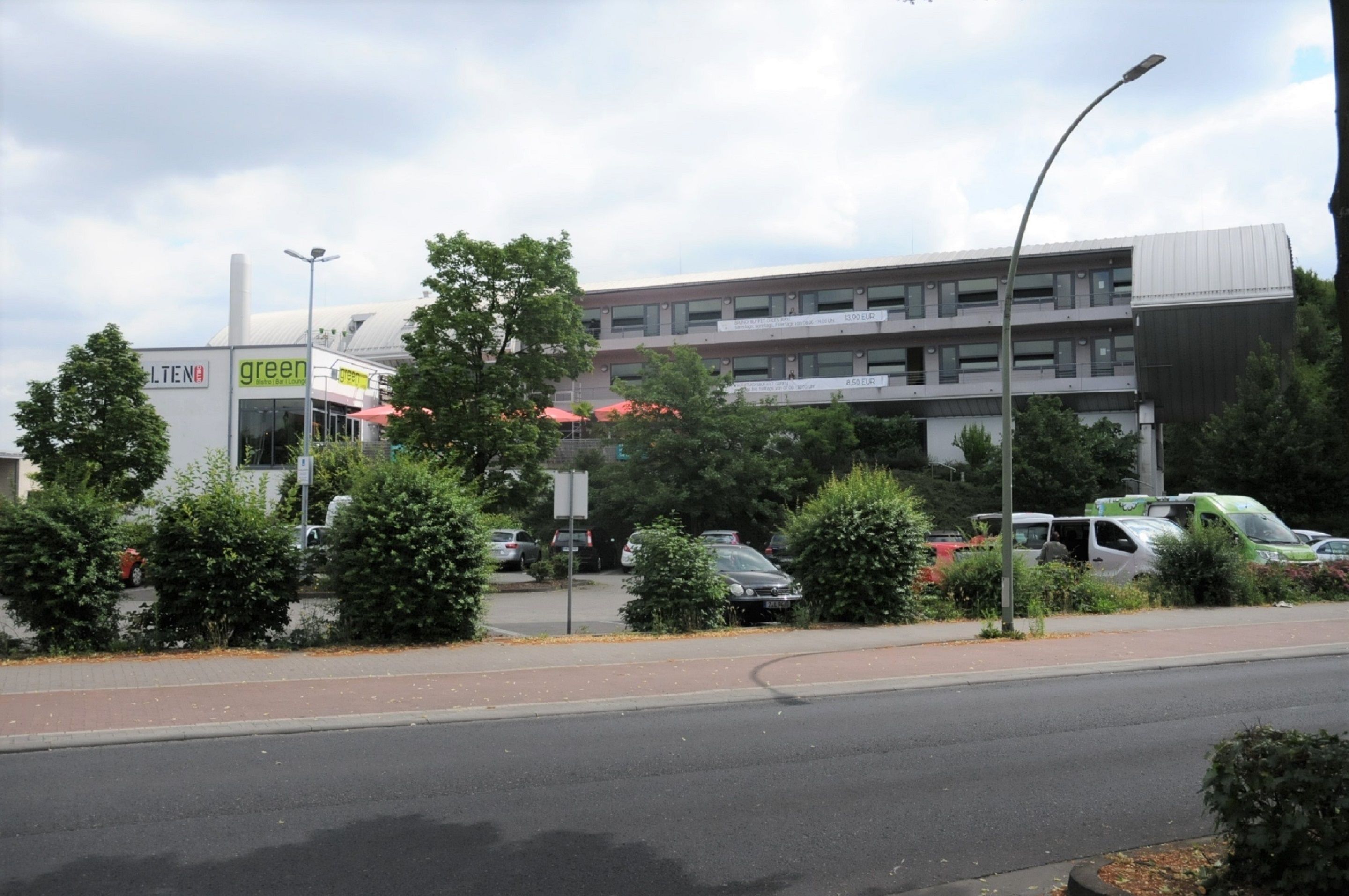 Ein mehrstöckiges Gebäude im modernen Stil, mit einem grünen Schild und einer roten Markise.