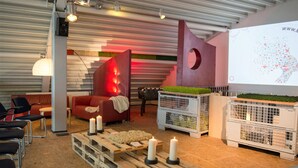Un espace de détente moderne avec un canapé rouge, une table basse en bois ornée de bougies et un écran de projection affichant un motif en forme de cœur.