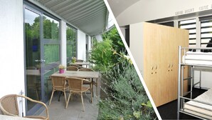 Une chambre moderne avec un lit superposé, une armoire en bois et un coin repas comprenant des chaises et une table en osier.