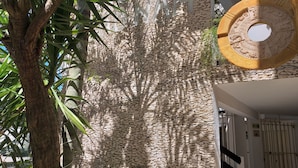 A stone wall with a circular architectural feature and a tree in the foreground. - Hotel Labnah (Playa del Carmen)