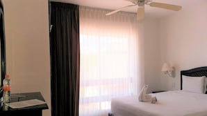 A hotel room with a bed, a nightstand, a ceiling fan, a window with curtains, and a wall-mounted lamp. - Hotel Labnah (Playa del Carmen)