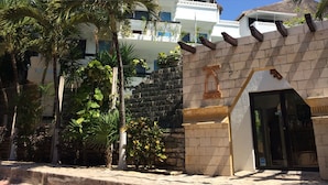 A building with a stone facade, a large entrance with a decorative arch, and a gated area with palm trees. - Hotel Labnah (Playa del Carmen)