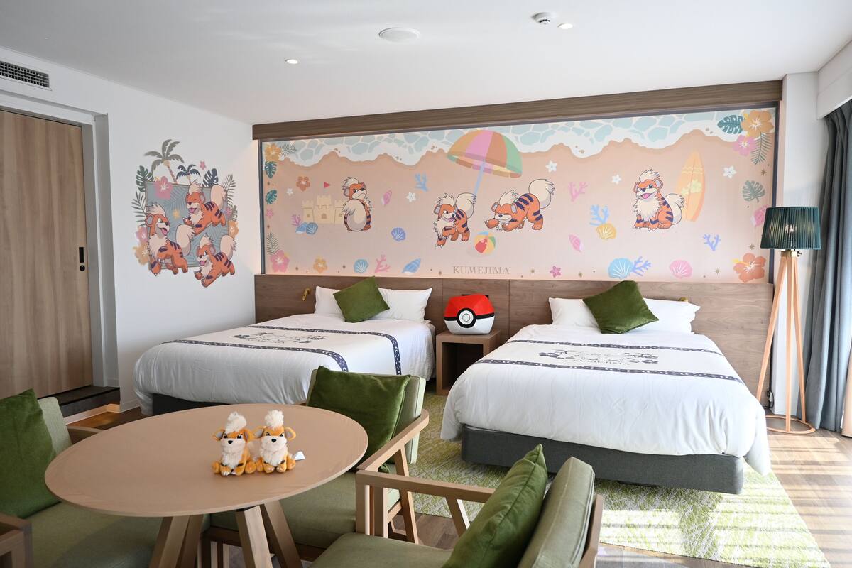 Une chambre d’hôtel avec deux lits, une table à manger et une fresque murale.