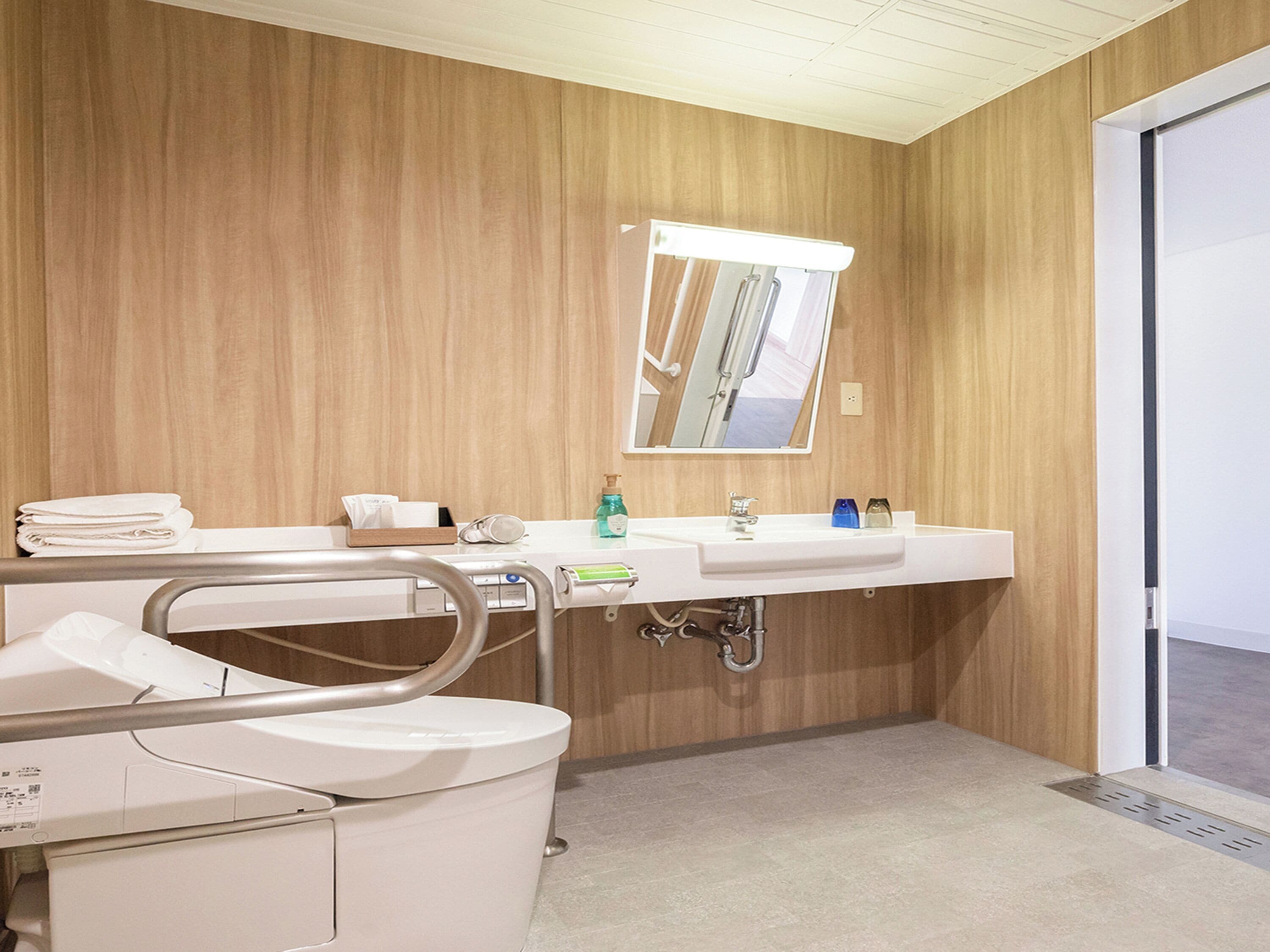 Une salle de bain moderne avec un mur en bois, un lavabo blanc et des toilettes.