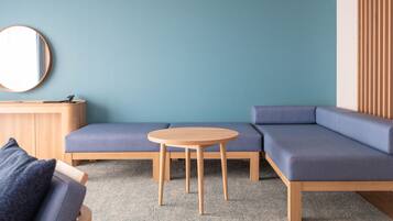 A modern living room with a sectional sofa, a round wooden table, and a round mirror on the wall.