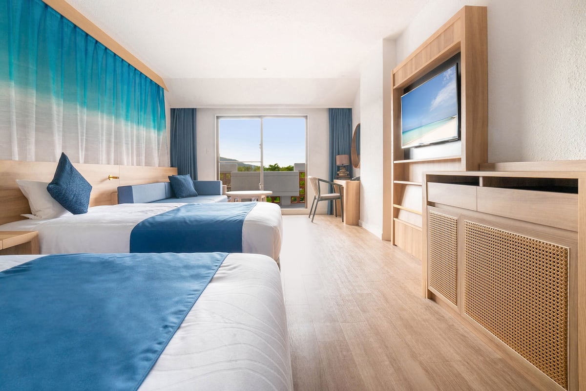 Une chambre d’hôtel moderne avec deux lits, une télévision et un balcon offrant une vue.