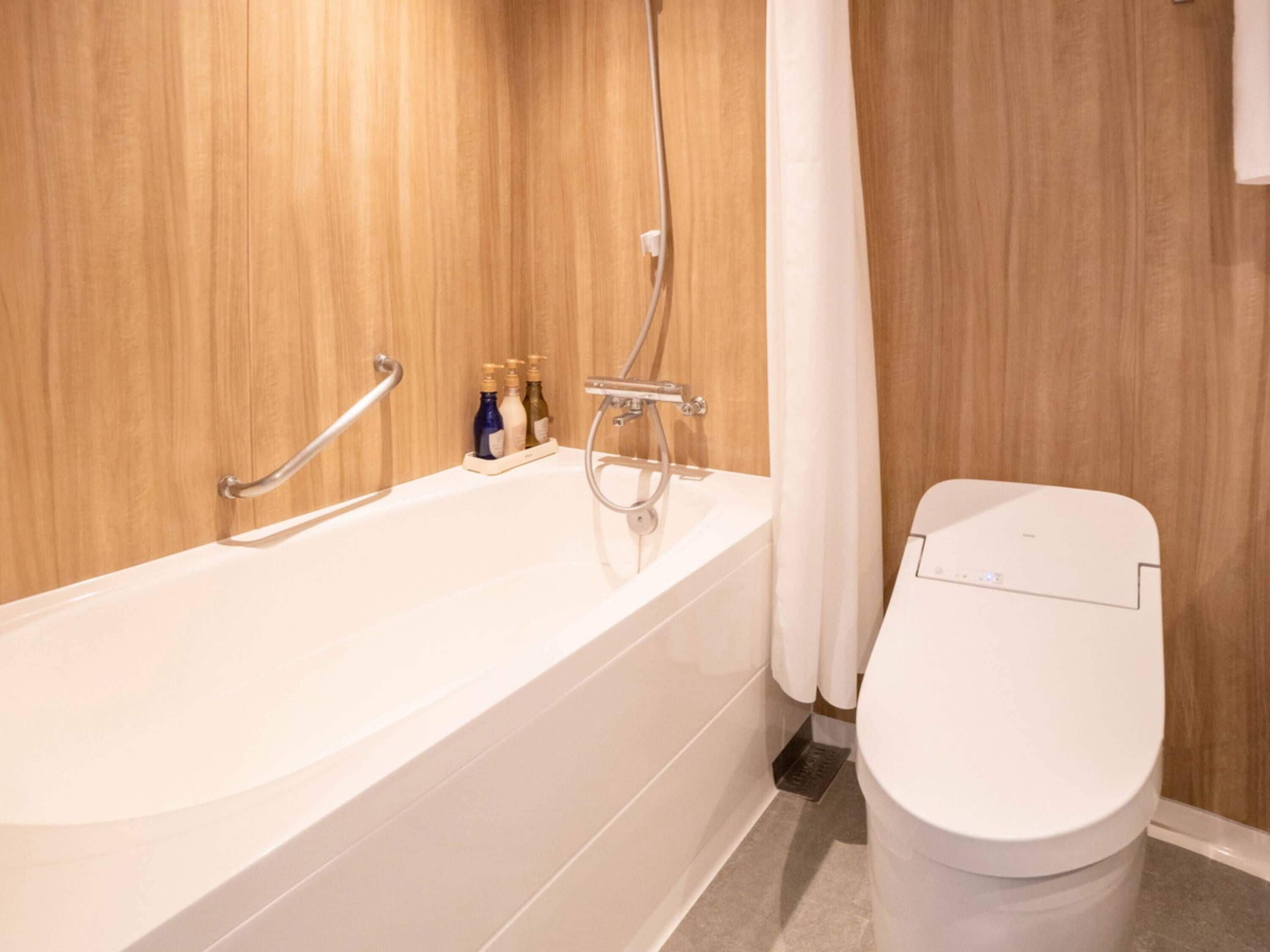 A bathroom with a bathtub, a toilet, and a shower area.