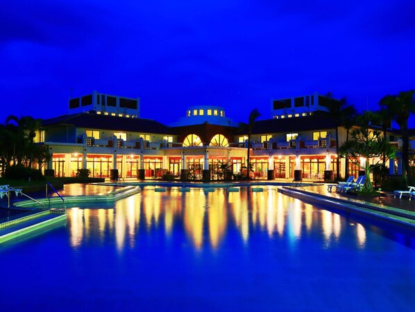 A hotel with a large pool, multiple dining areas, and a central atrium.