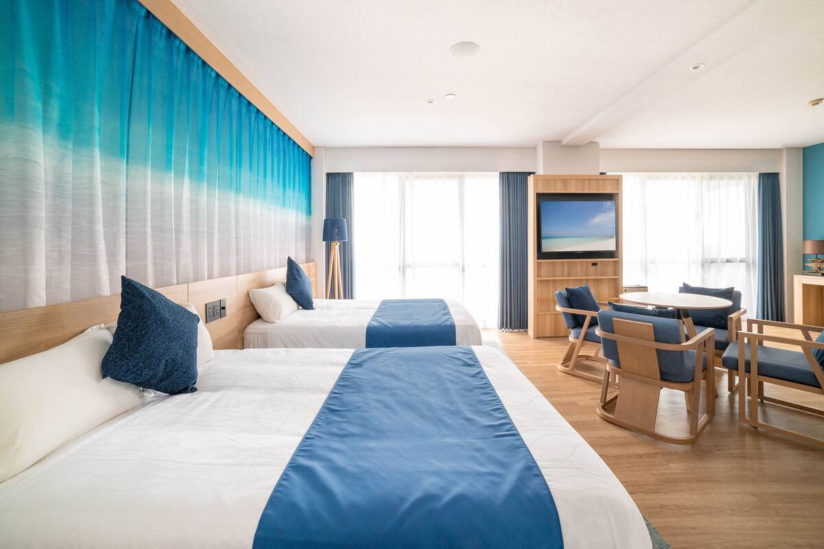 Une chambre d’hôtel avec deux lits, un bureau et une télévision.