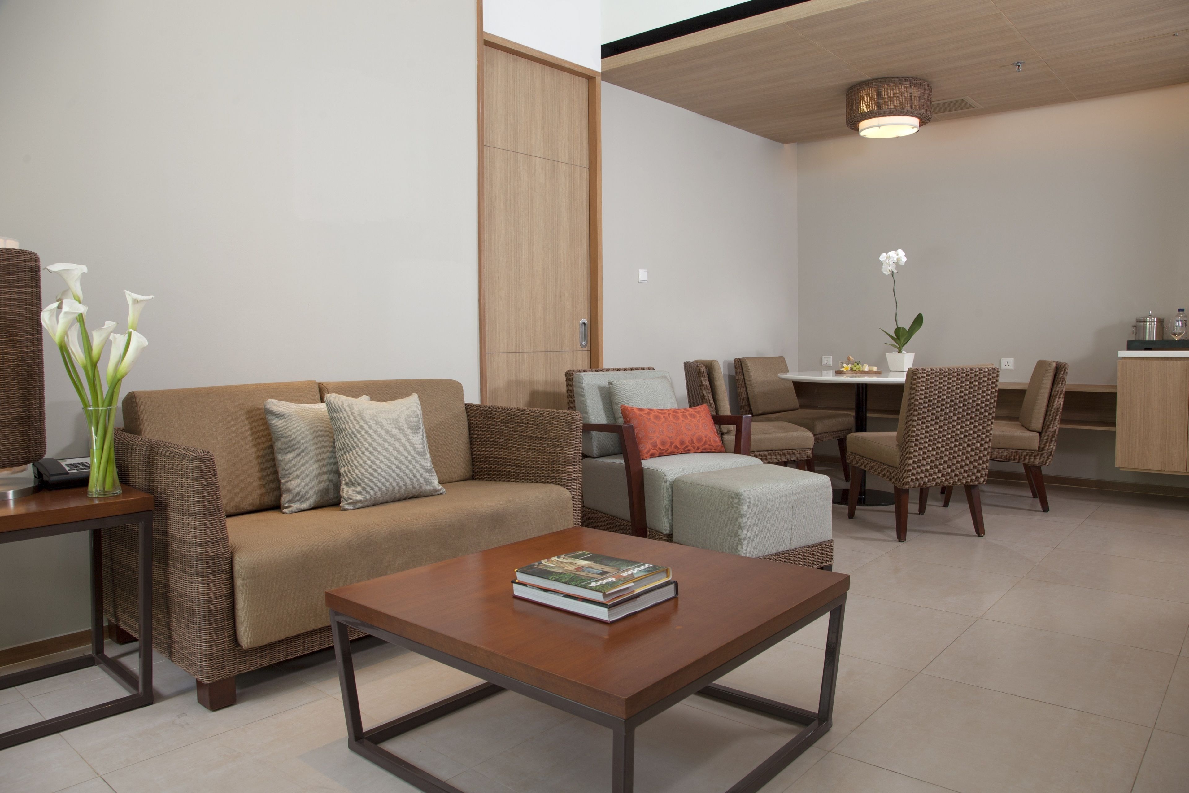 A modern living room with a sofa, armchairs, a coffee table, and a dining area with chairs and a table.