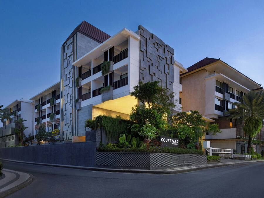 Ein mehrstöckiges Hotel mit Innenhof, das moderne Architektur mit geometrischen Mustern und Balkonen aufweist.