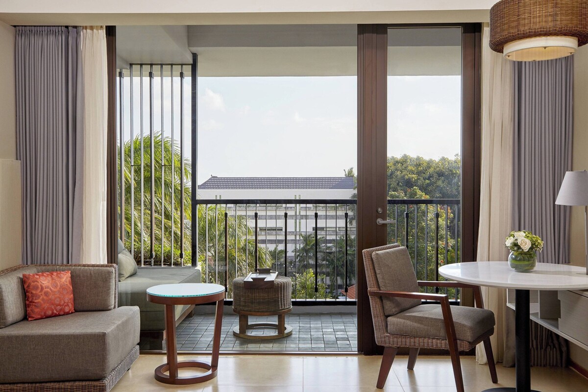A balcony with a sofa, chairs, a small table, and a lamp.