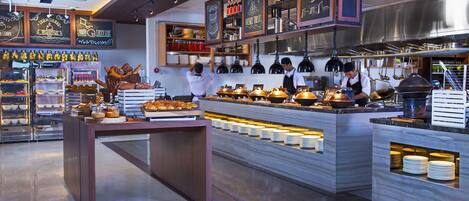 A modern café with a counter displaying pastries and beverages, a chalkboard menu, and a clean, well-lit interior.