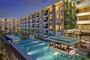 Um hotel moderno com uma grande piscina ao ar livre, várias varandas e um terraço no terraço.
