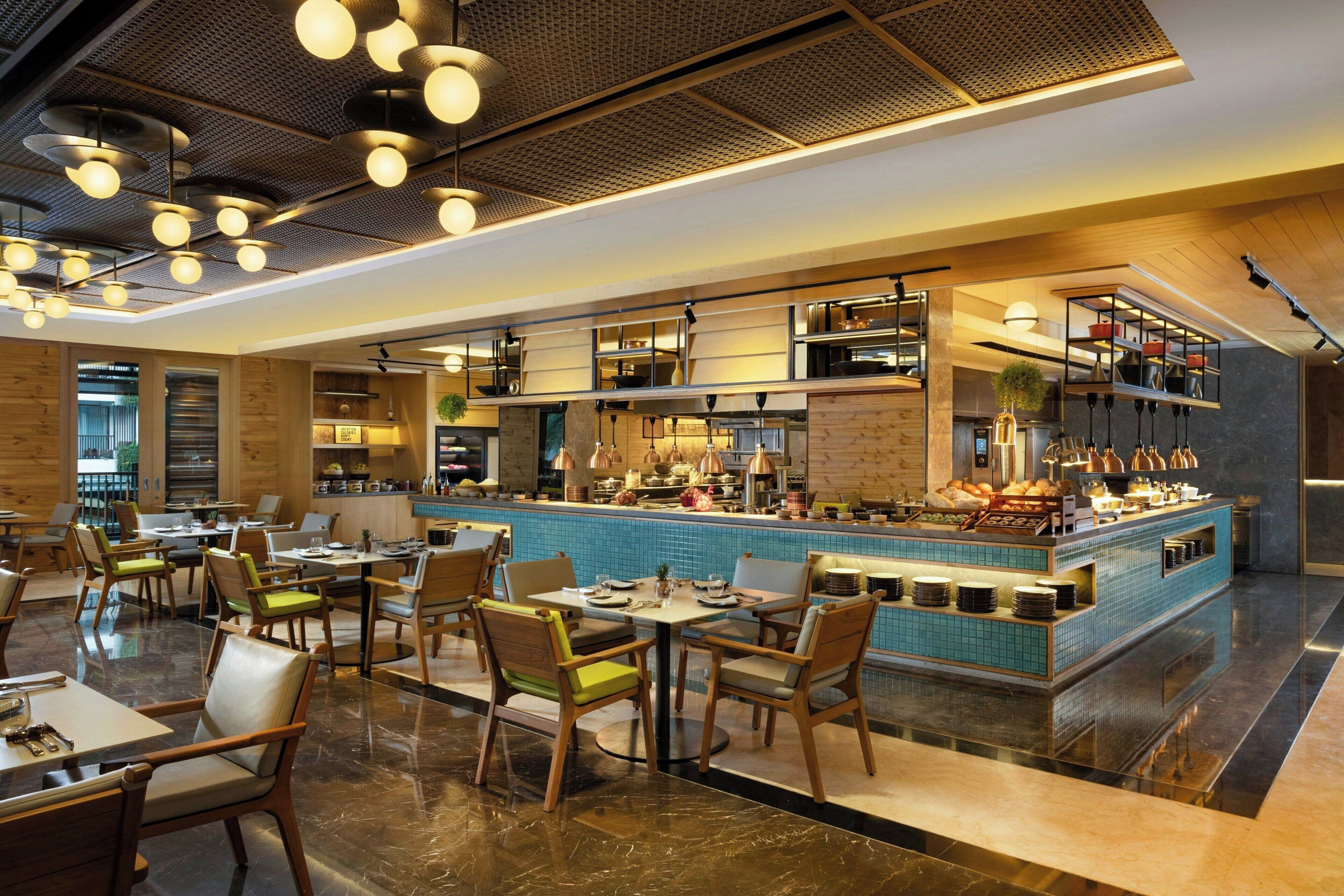 A modern restaurant with a central bar area, wooden furniture, and a tiled backsplash.