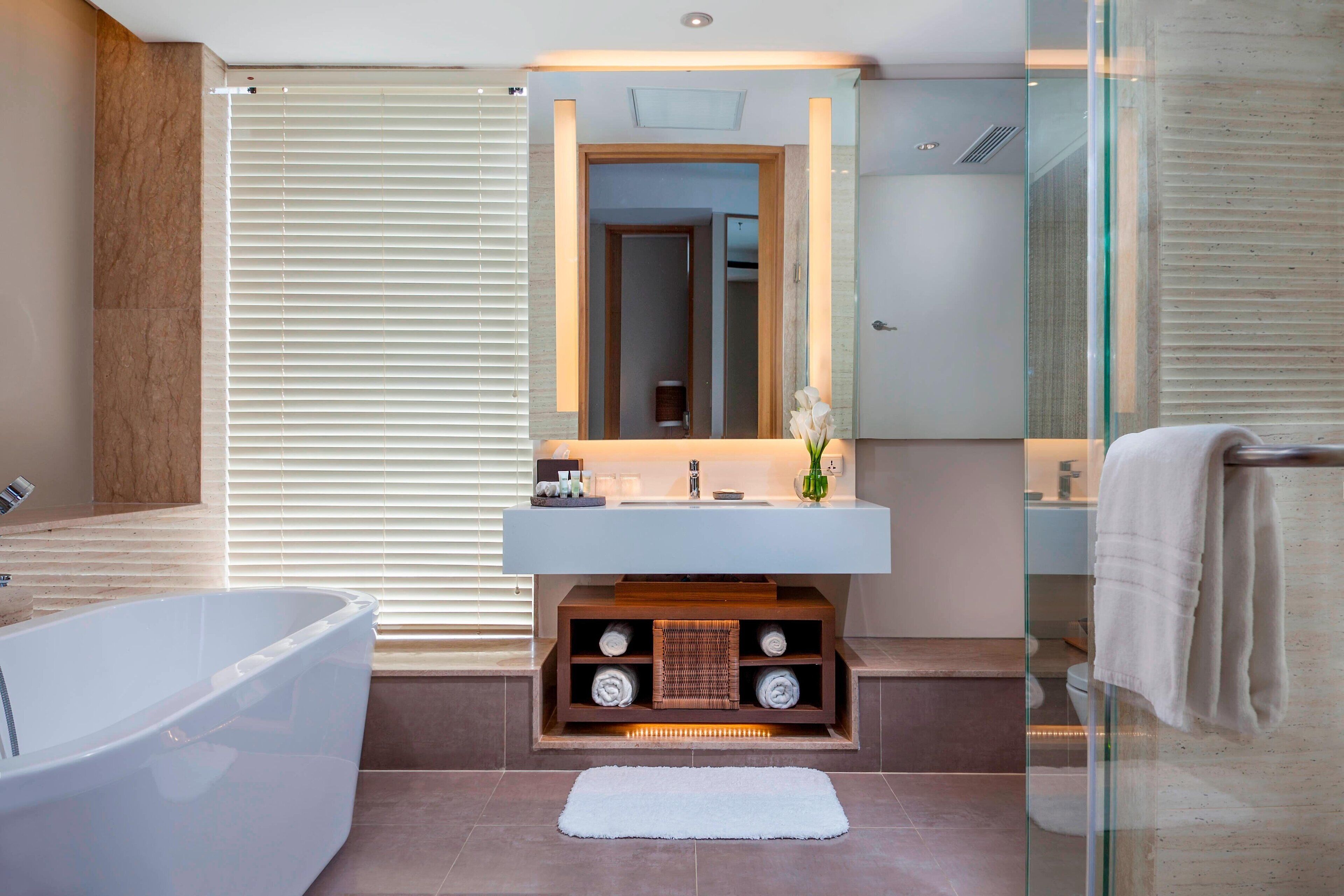 A modern bathroom with a freestanding bathtub, a glass-enclosed vanity with a mirror, and a towel rack.