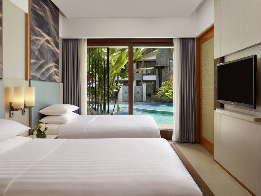 Una camera d'albergo con un letto grande, una televisione e vista sulla piscina.