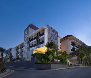 Un hotel de varios pisos con un patio, arquitectura moderna y una cerca a cuadros.