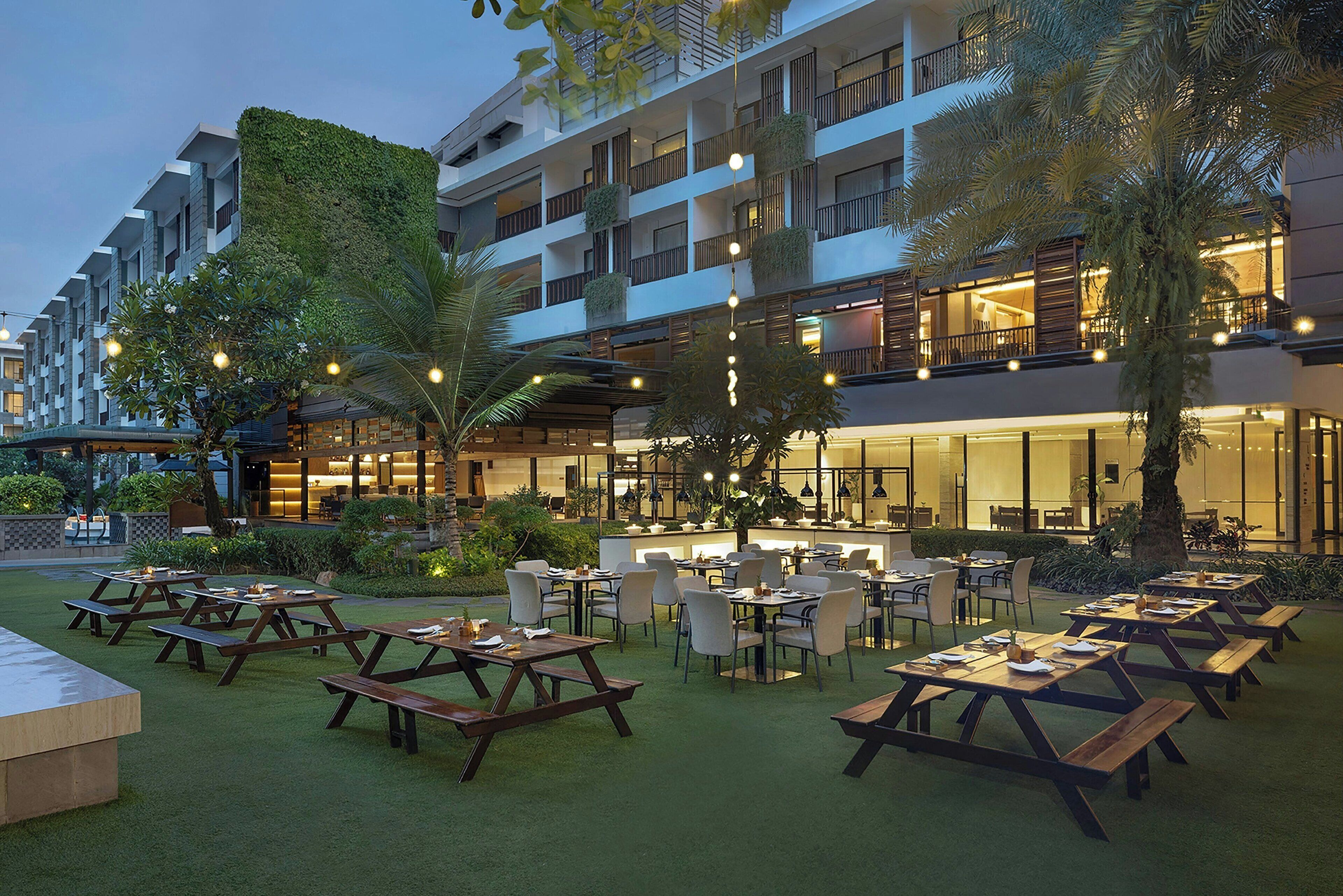 A hotel courtyard with outdoor seating and a modern building with balconies.