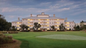 A large, multi-story hotel with a well-maintained lawn and a golf course in the foreground. - Club Wyndham Dye Villas (North Myrtle Beach)
