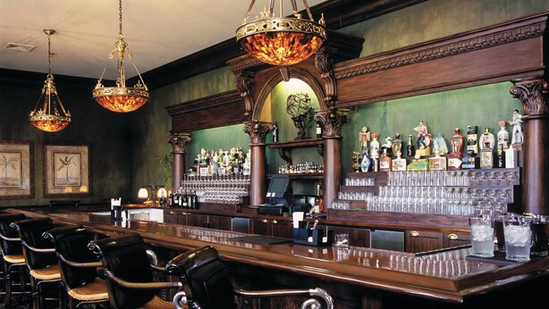 A bar area with a long counter, multiple chairs, and ornate chandeliers. - Club Wyndham Dye Villas (North Myrtle Beach)