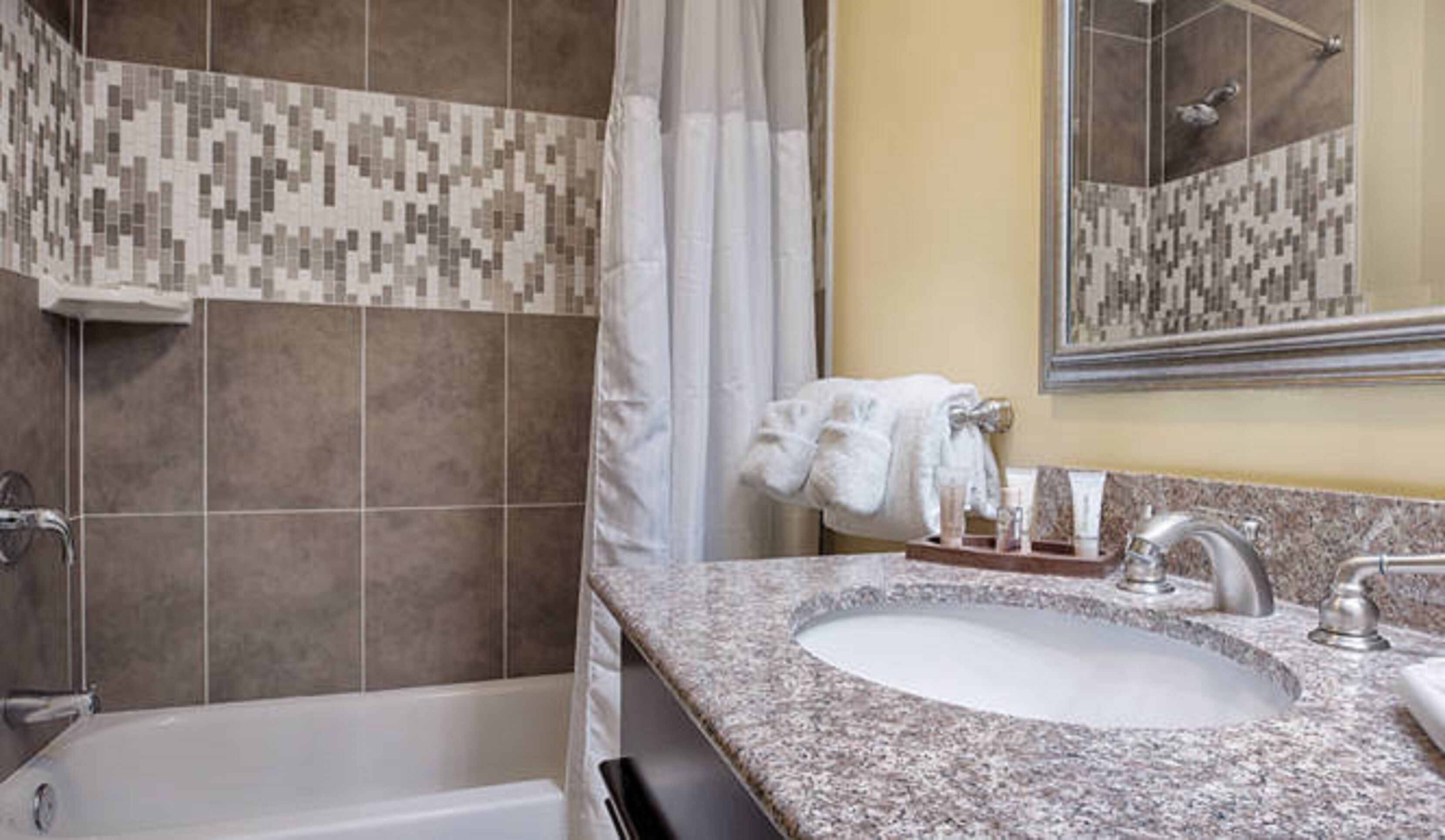 Un baño con bañera, lavabo, espejo y cortina de ducha.