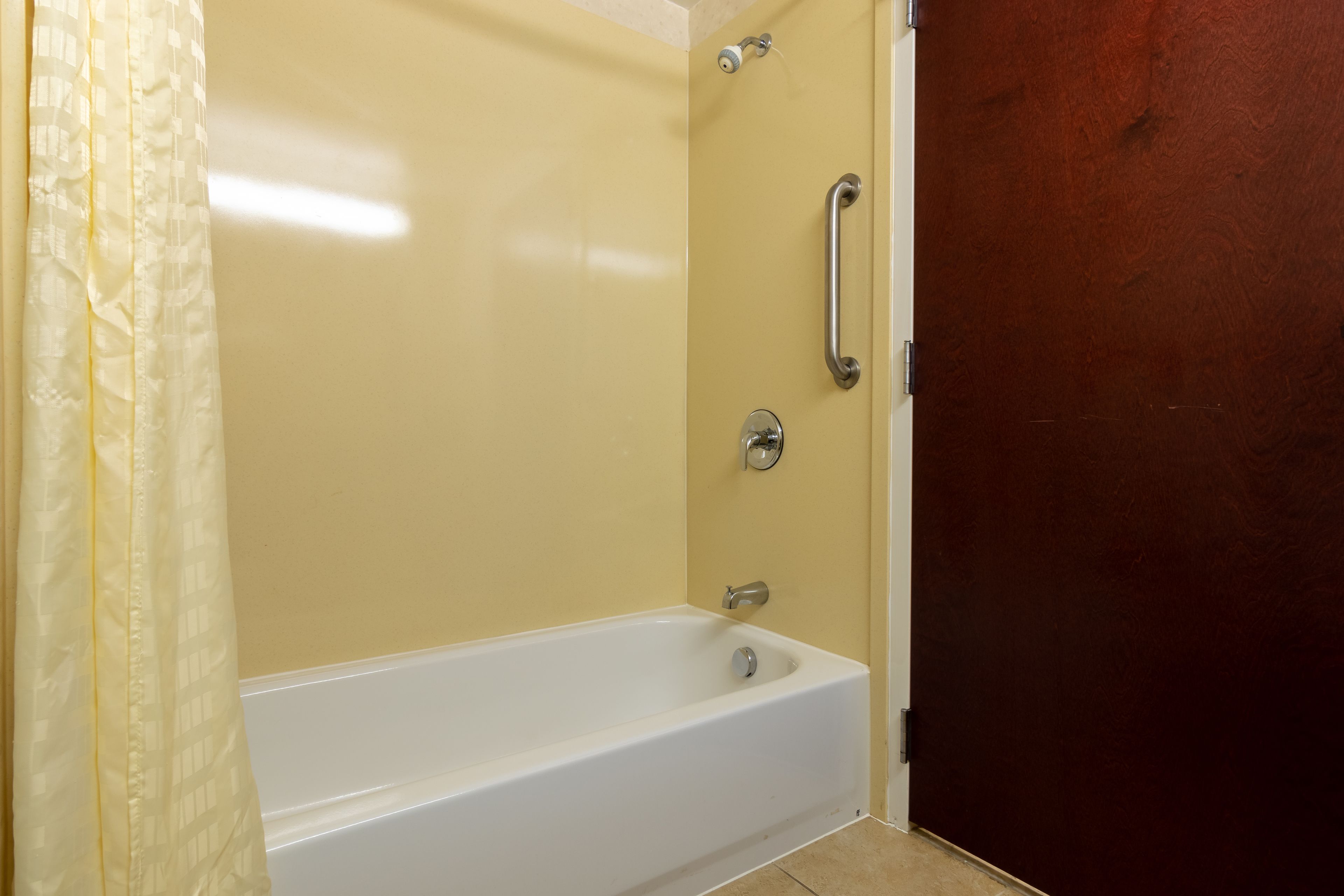 A bathroom with a bathtub, a shower curtain, and a wooden door.