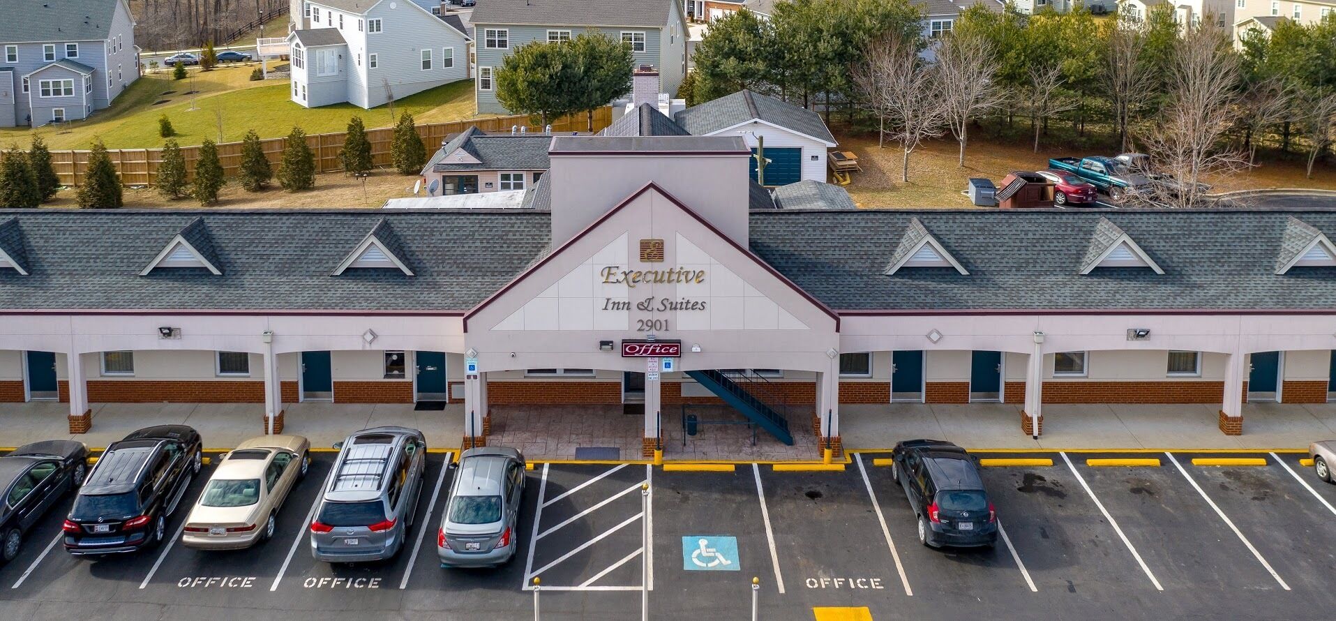 Een gebouw van Executive Inn Suites met een parkeerplaats en meerdere auto's.