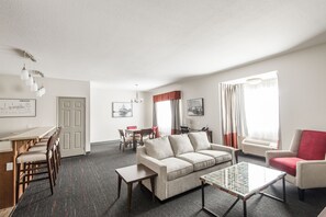 A modern living room with a sofa, coffee table, and dining area. - Edgewater Hotel (Whitehorse)
