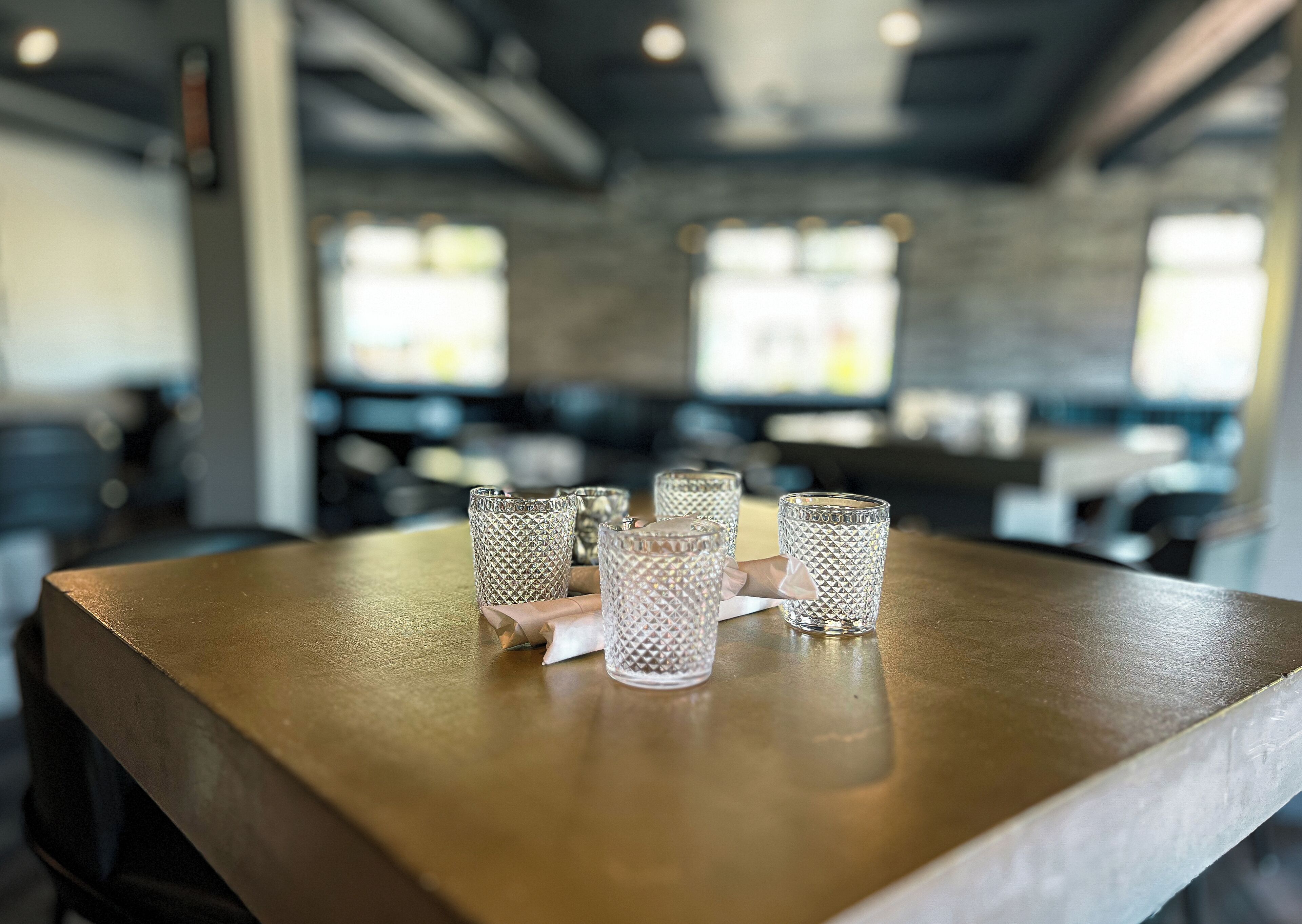 A table with four clear glass tumblers and a napkin.