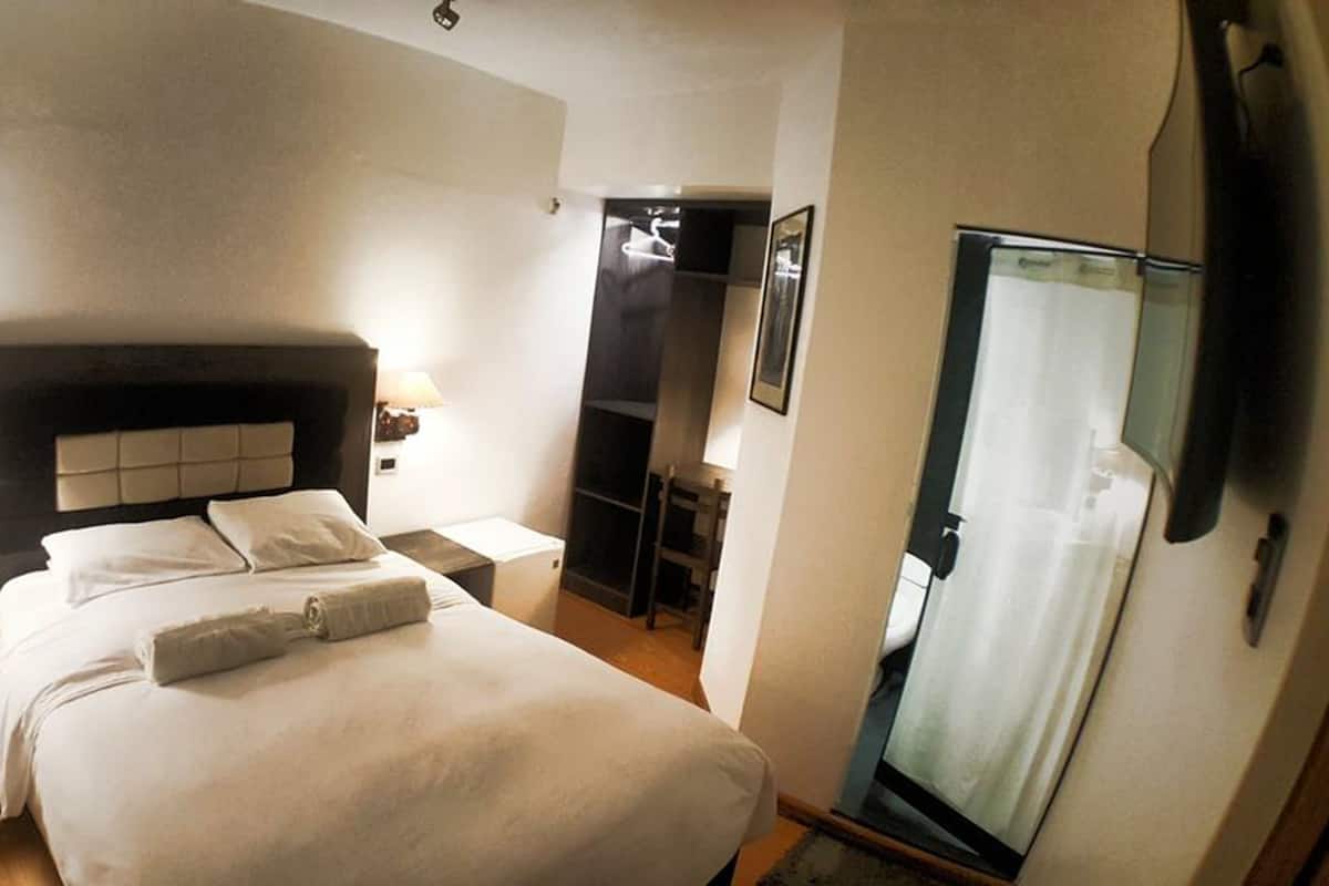 Une chambre d’hôtel comprenant un lit, des tables de chevet, une armoire et un miroir.