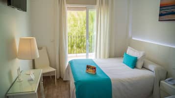 Une chambre d’hôtel avec un lit, un bureau, une chaise, une télévision et un balcon avec des rideaux.
