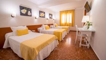 Une chambre d’hôtel avec trois lits, un bureau et une chaise.