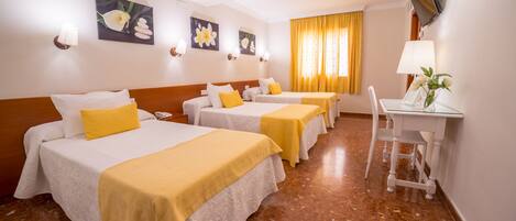 A hotel room with three beds, a desk, and a chair.