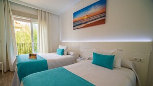 A hotel room with two beds, each with a teal bedspread and white pillows, a painting of a sunset on the wall, and a window with curtains. - Hotel Romerito (Málaga)