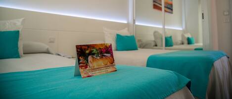 A hotel room with two beds, teal bedding, a painting of a sunset, and a mirror reflecting the room.
