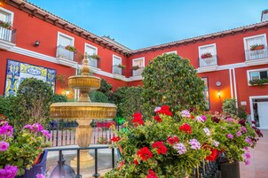 Un patio con fuente, plantas en macetas y un edificio con balcones.