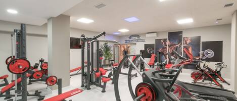 Un gimnasio con varios equipos de ejercicio, incluyendo máquinas de pesas y máquinas de cardio.