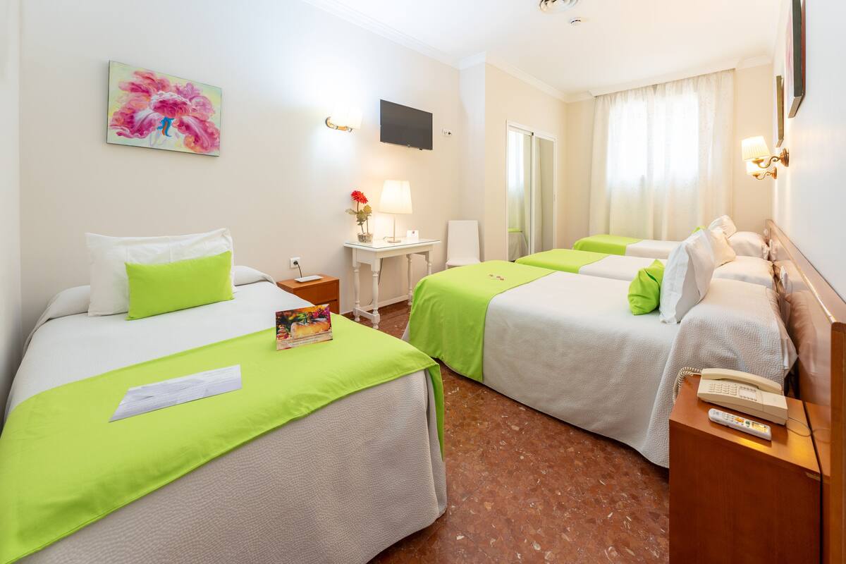 Una habitación de hotel con dos camas, un escritorio, una silla, un televisor y un teléfono.
