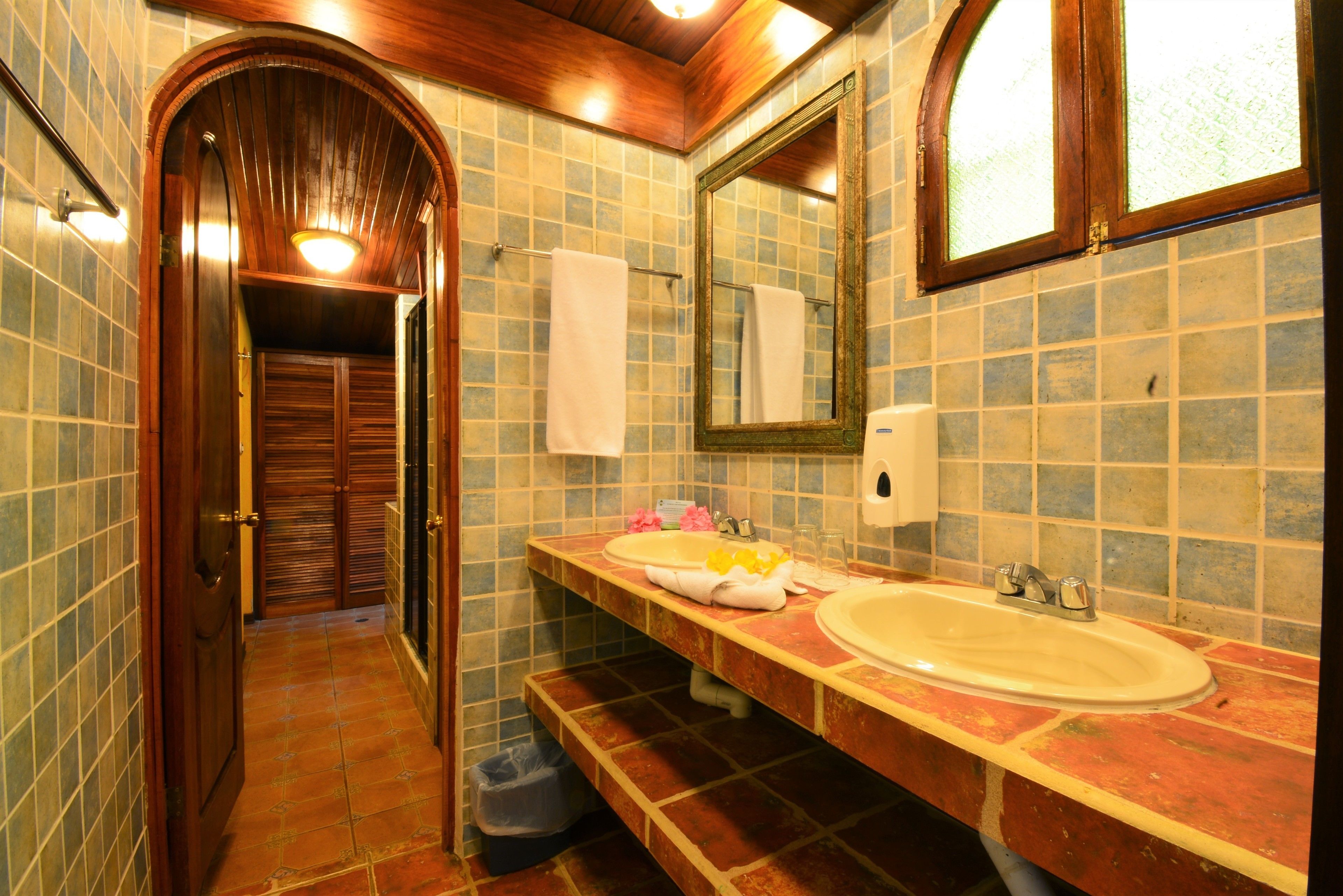 A bathroom with a wooden door, a large mirror, and two sinks.