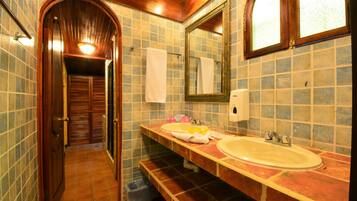 A bathroom with a wooden door, a large mirror, and two sinks.