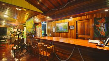 Angolo bar in legno con soffitto alto, sgabelli da bar e opere d'arte alle pareti.