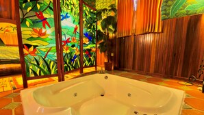 A large, white bathtub in a room with wooden paneling and colorful stained glass windows. - La Mansion Inn Arenal (Arenal)