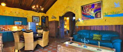 Un comedor con mesa y sillas de madera, un sofá azul y un mural colorido en la pared.