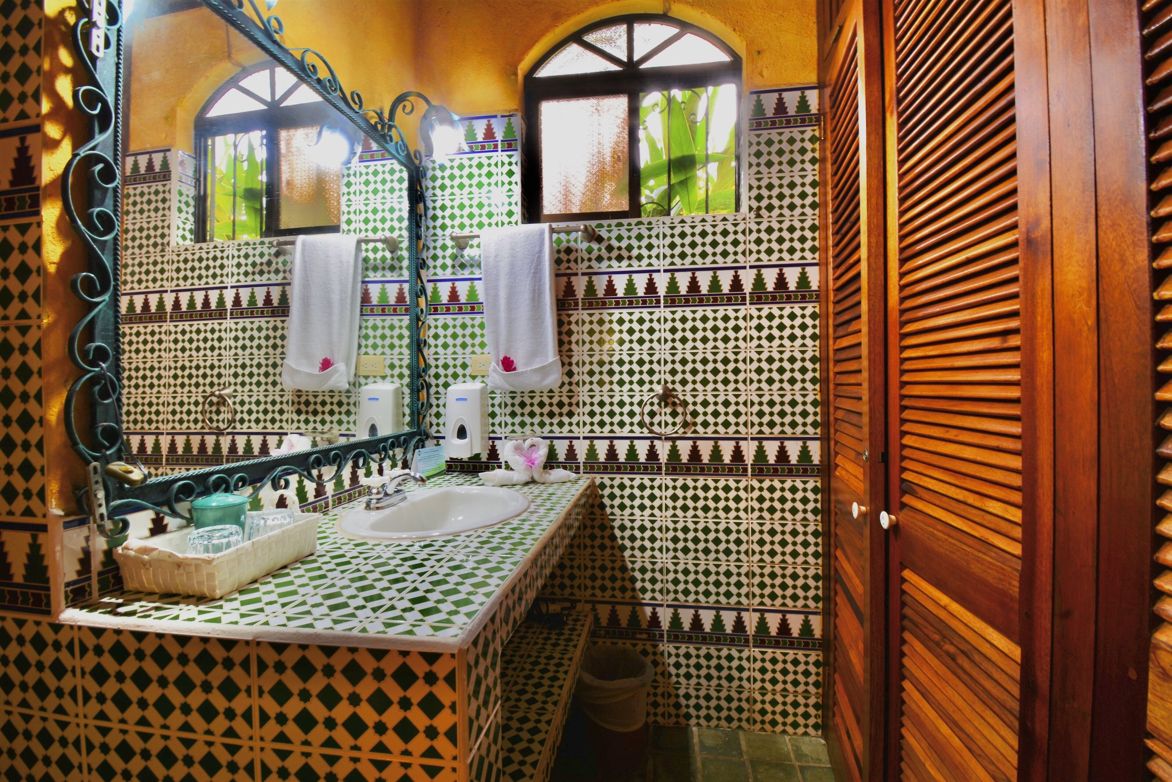 Un baño con piso de baldosas, un lavamanos, un espejo y una ventana.