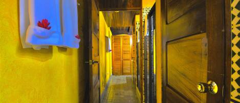 Un pasillo estrecho con puertas de madera y paredes amarillas.