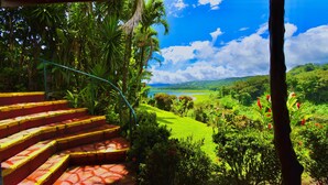 A staircase leading to a lush garden with a view of a green landscape and a clear blue sky. - La Mansion Inn Arenal (Arenal)