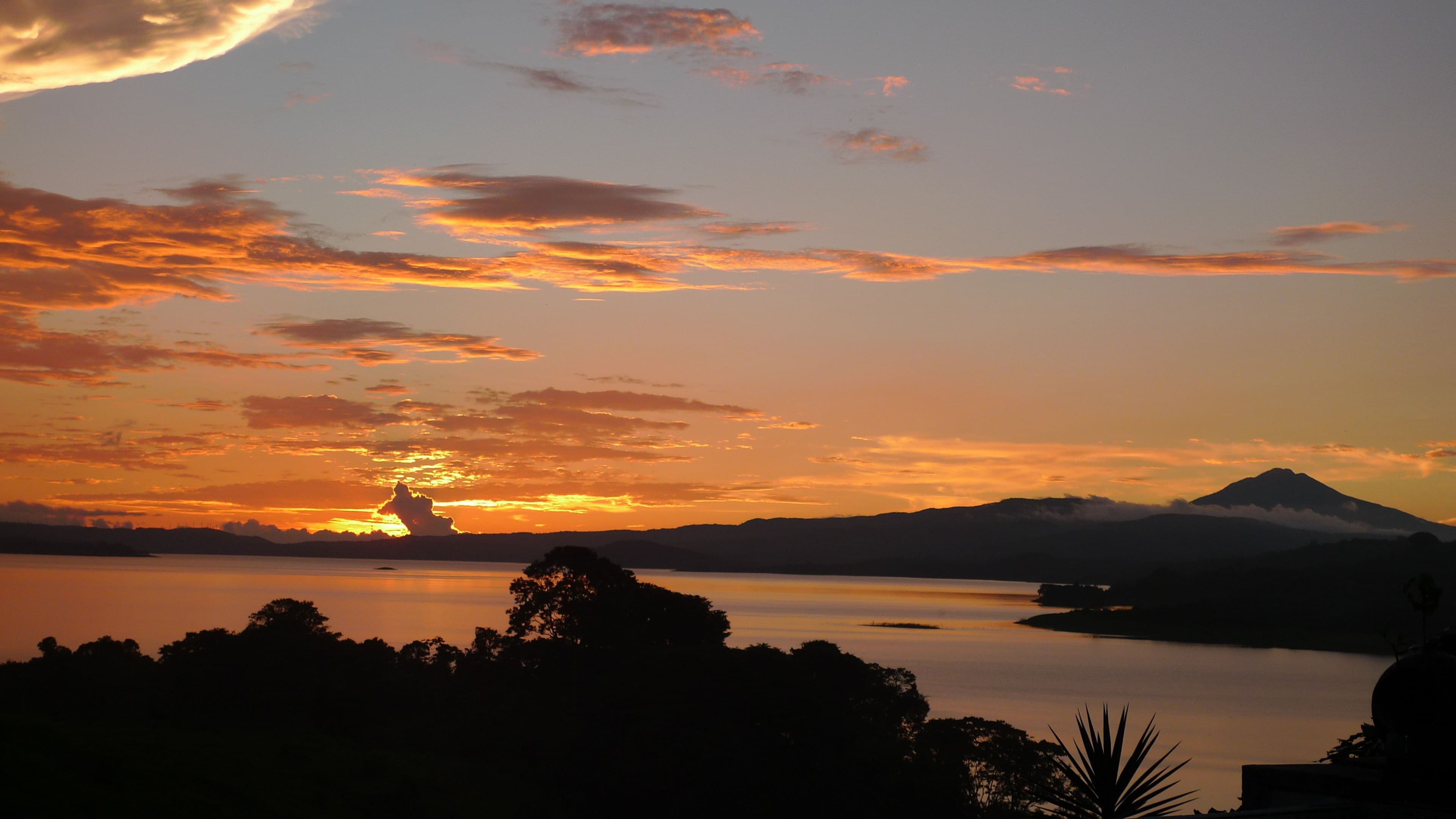 A sunset over a calm lake with mountains in the background.